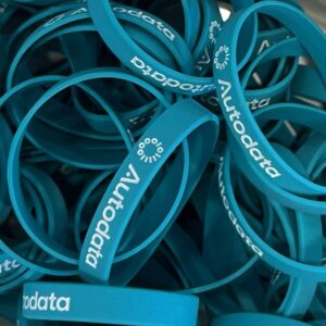 A pile of blue silicone wristbands with the word Autodata, a circular logo, and a nod to Life in London printed in white on each band.